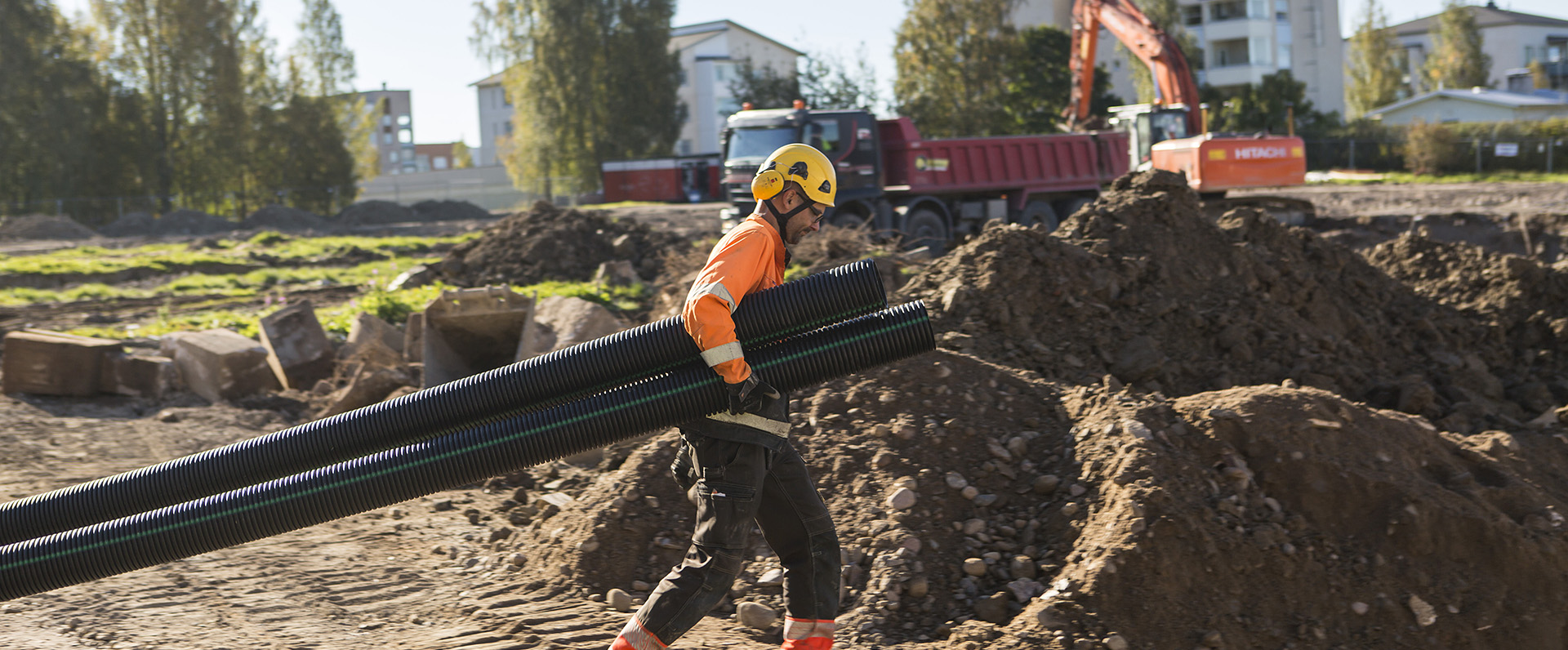 Mies kantaa muoviputkia työmaalla